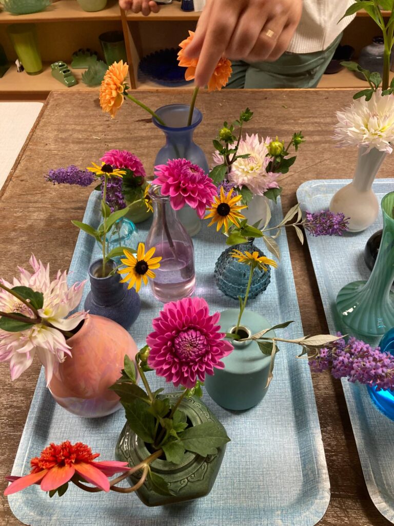 Verschillende kleine vaasjes met bloemen die bij de ontvangst voor deelnemers van het traject Vrouw-zijn worden klaargezet