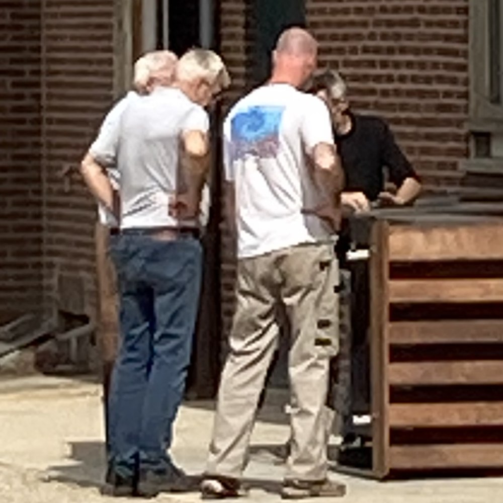 Een klein groepje mensen staat buiten bij het gebouw bij elkaar