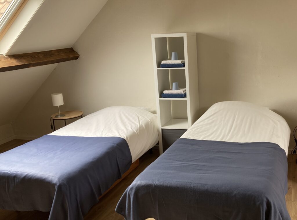 Tweepersoons zolderkamer met twee bedden onder de schuine kap
