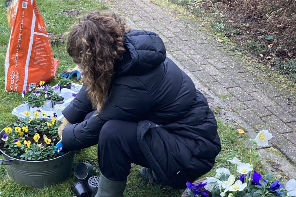Iemand werkt geconcentreerd tussen de bloemen in de tuin van de Leonardushoeve