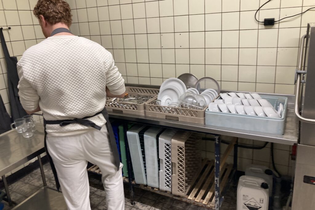 Iemand ruimt in de afwaskeuken servies op tijdens werkmeditatie