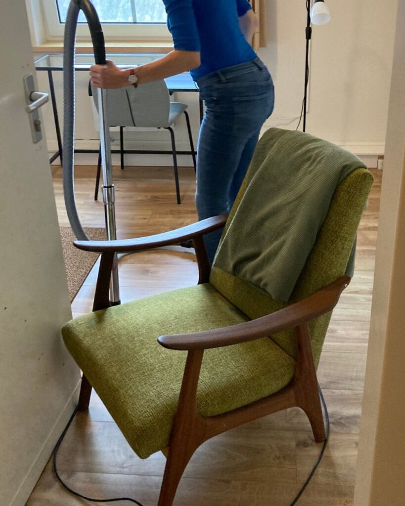 Werkmeditatie in de praktijk: een stofzuiger in gebruik in een gastenkamer, met een groene fauteuil op de voorgrond